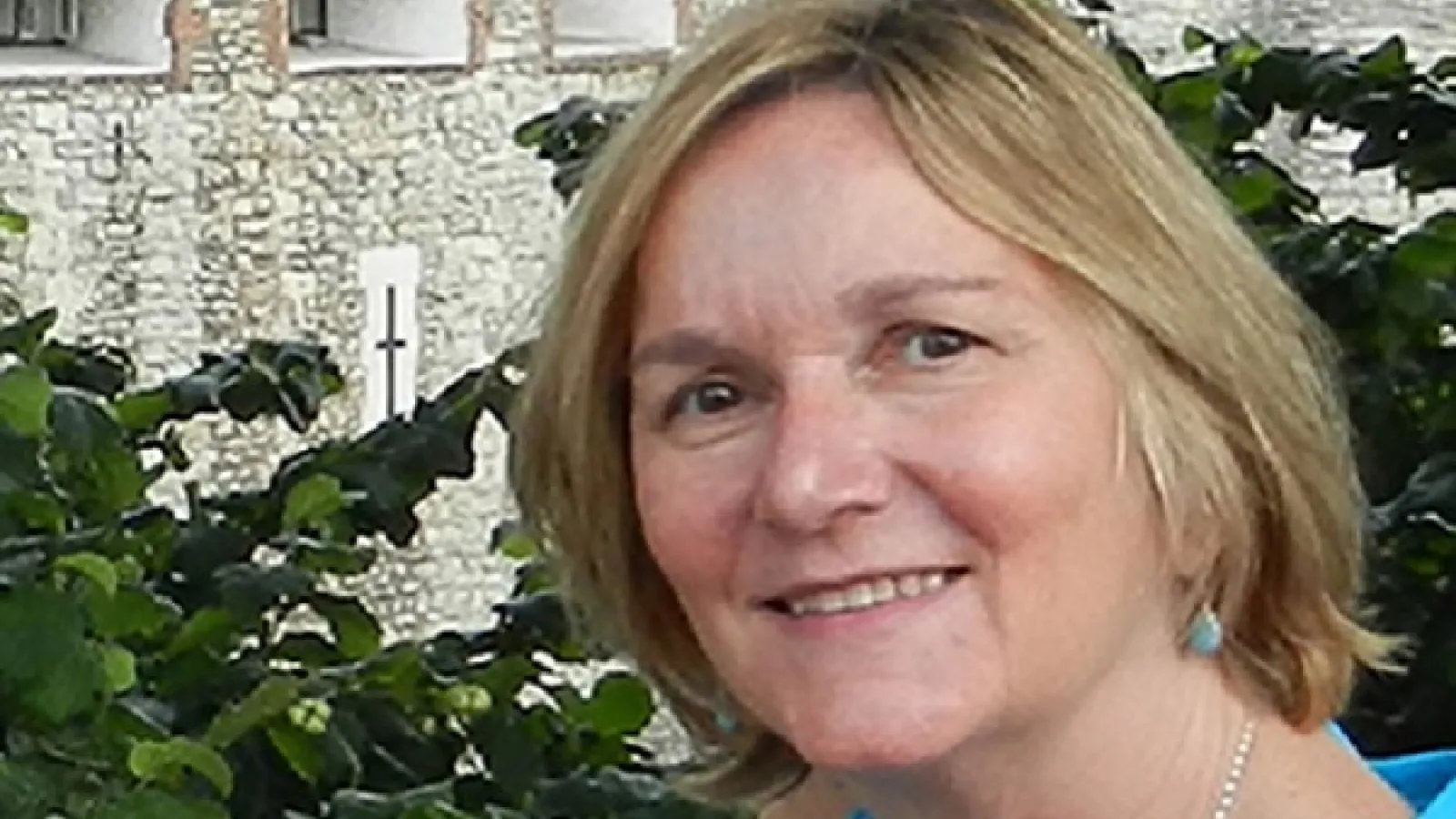 Professor Lucy Murphy in a blue shirt in front of a building.