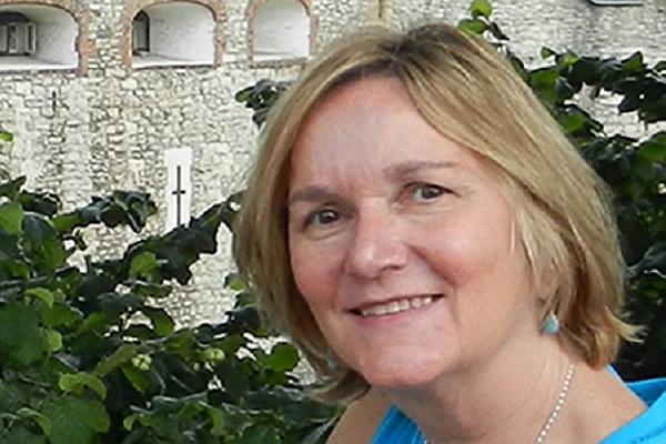 Professor Lucy Murphy in a blue shirt in front of a building.