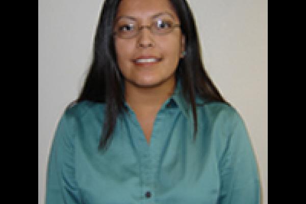 Shanna Ketchum Heap of Birds, a woman with brown skin, black hair, and a blue shirt looks directly at the camera