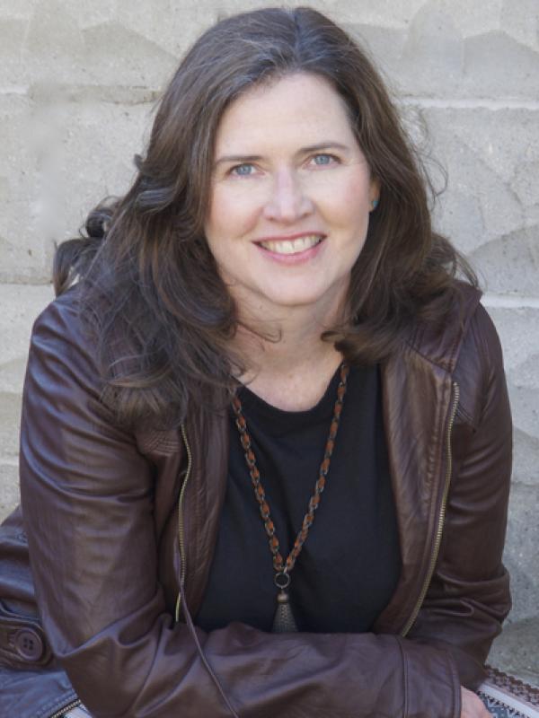 A woman smiling at the camera in a brown jacket